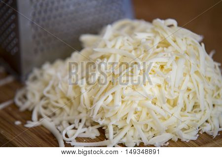 Shredded Mozzarella Cheese On A Cutting Board With A Grater