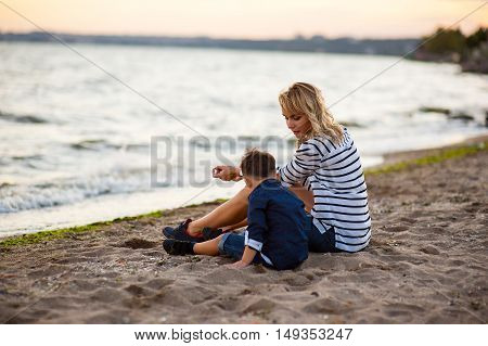 Beautiful woman with a child of four years playing on the beach near the sea