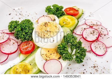 Cucumber laid out on a white plate with slices of radish, carnations