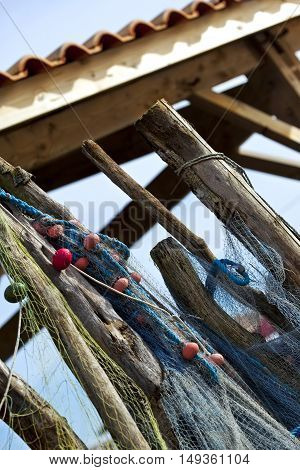Fishing nets and buoys hanging on wooden stakes front of a fisherman's hut