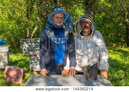 Portrain of Ukrainian bee-keeper and his assistant at work place