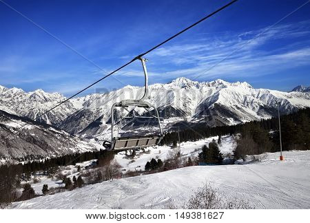 Ski Slope And Chair-lift In Snow Winter Mountains At Sun Windy Day