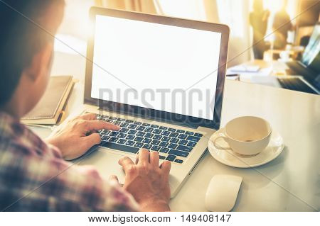 side view of the laptop is on the work table in a conner office with morning light.