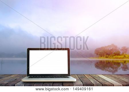 Laptop on wood floor perspective on the lake and forest backgrounds.Mock up for display or montage of productBusiness presentation