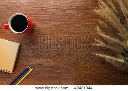 workspace with coffee pencils notebook and grass on wooden table