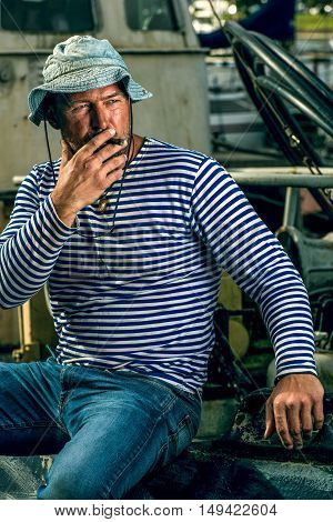Old salt man smoking on his rusted ship