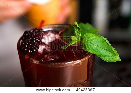 Closeup of healthy sweet berry non-alcoholic party cocktail at restaurant background. Refreshing drink with ice, blackberries and mint dusted with sugar