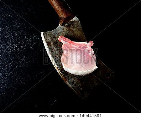pork steak and vintage cleaver on a black background