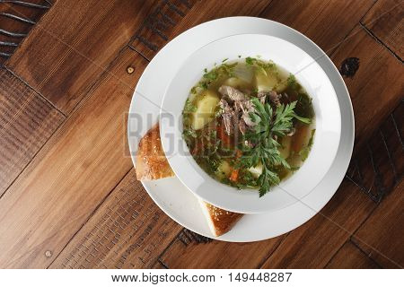 Chorba - traditional middle eastern soup in a white plate. Wooden background.