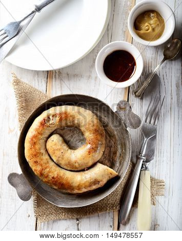fragrant juicy homemade sausages in a pan, fork on a napkin