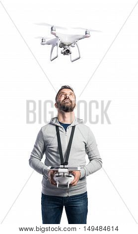 Man with remote control and flying drone with camera. Studio shot on white background, isolated.