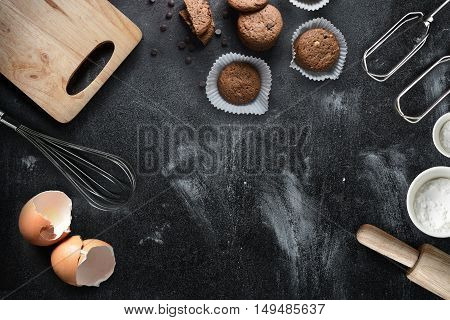 Kitchen text with kitchen utensils and baking ingredients: egg and flour on black background copy-space.