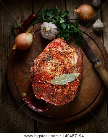 raw piece of pork, onion, pepper, garlic, fresh herbs on the wooden background