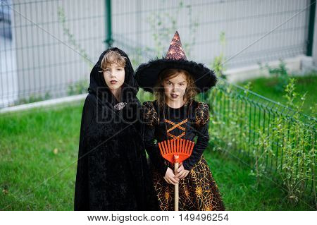 Two children brother and sister are dressed in suits for Halloween. Boy represents the magician girl - the magician. Children stand on a green lawn. They are ready to go behind sweets.Children like Halloween.