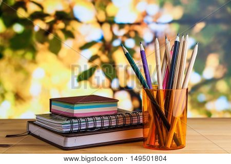 Stationery notepad address book notes pencils in a glass on a wooden table.