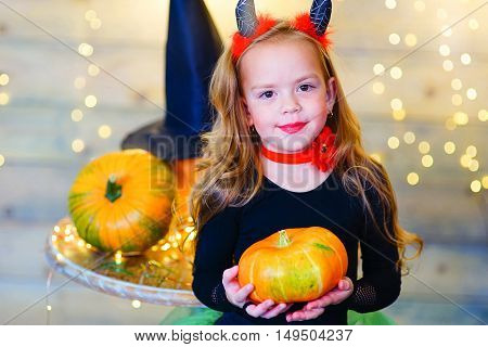 Happy deamon children during Halloween party playing around the table with pumpkins