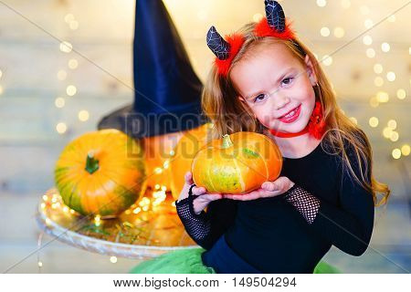 Happy deamon children during Halloween party playing around the table with pumpkins