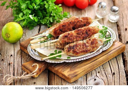 Homemade meat kebabs skewers with dogberry and onion salad on wooden background.