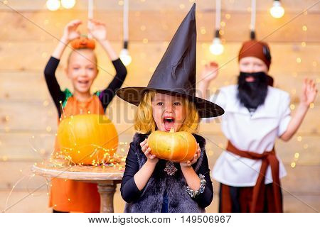 Happy group of pirate and witch children during Halloween party playing around the table with pumpkins