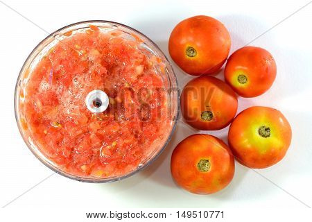 Crushed tomato and fresh tomato on a white background.