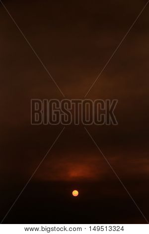 Summer sunset and orange sun over dramatic red clouds