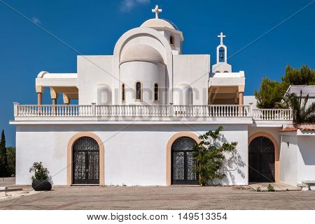 View of the Orthodox church with white walls in the Greek village of Anavisos in the summer sunny day.