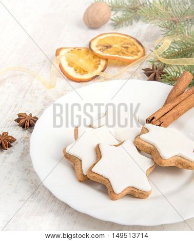 Close up of homemade butter nuts star shaped cookies with icing pine orange slicescinnamon anise walnuts and golden ribbon over white wood background. Christmas decoration.