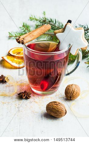 Homemade butter nuts star shaped cookie with icing pine orange slicescinnamon anise walnuts and golden ribbon over white wood background. A cup of berry tea. Christmas decoration.