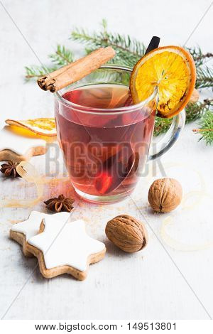 Homemade butter nuts star shaped cookies with icing pine orange slicescinnamon anise walnuts and golden ribbon over white wood background. A cup of berry tea. Christmas decoration.