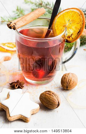Homemade butter nuts star shaped cookies with icing pine orange slicescinnamon anise walnuts and golden ribbon over white wood background. A cup of berry tea. Christmas decoration.