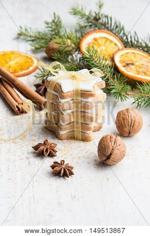 Close up of homemade butter nuts star shaped cookies with icing pine orange slicescinnamon anise walnuts and golden ribbon over white wood background. Christmas decoration.
