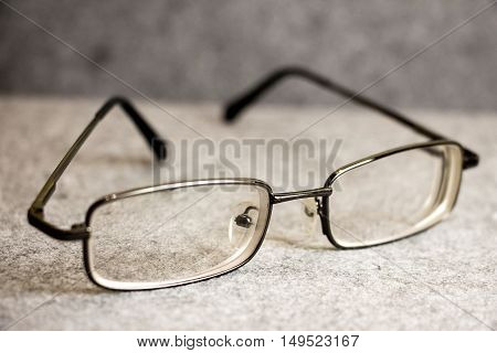 Men's glasses with a thin rim on a gray background closeup
