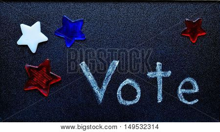 Vote written on blackboard surrounded by red, white and blue stars.  Election symbol for local and national campaigns.