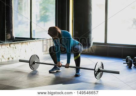 Muscular woman in a gym doing heavy weight exercises. Young woman doing weight lifting at health club.
