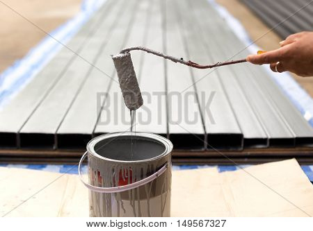 Worker dripping paint with paintroller on construction site