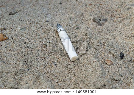lonely cigarette butt on the sand pollutes it