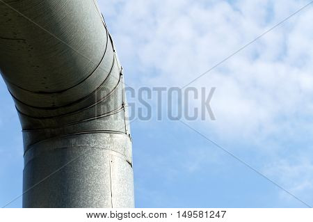 Curve old pipe (with stainless steel) on a background of blue sky with white clouds.