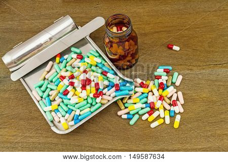 Colorful tablets medicine in the drug counting tray and black bottle on wooden background