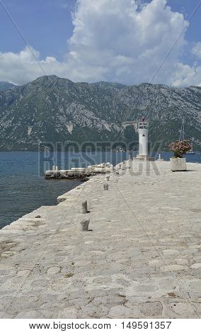 The artificially created island Our Lady of the Rock island in Kotor Bay Montenegro. A small oleander plant can be seen in the centre right and a small lighthouse in the background