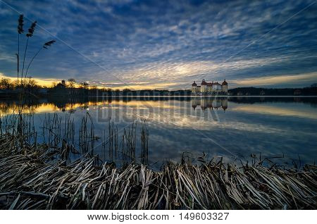 The Moritzburg Castle is a Baroque palace in Moritzburg in the German state of Saxony. Beautiful sunset with amazing clouds and water reflection during spring time Saxony Germany.