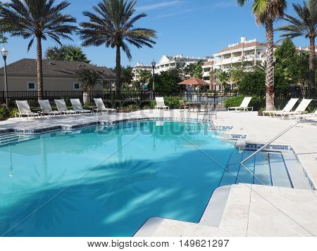 large inground swimming pool at a tropical resort. There are lounge chairs around the pool but no people.
