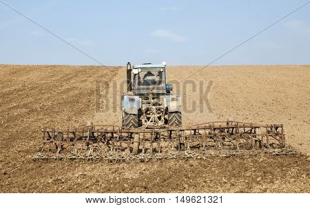 Harrowing the soil with tine harrows in spring in Ukraine.