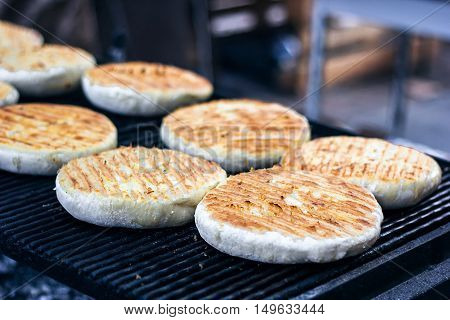 Georgian traditional dish khachapuri, pastry flat cake cheese-filled bread fried on the grill, BBQ. Fresh hot tasty street food in the market. Cooking food. Preparation dish of Middle Eastern cuisine.