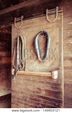 Various horse tack items hang in a stable.