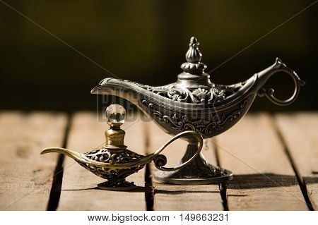 Beautiful antique metal lamp in true Aladin style, smaller model placed next to it, sitting on wooden surface.