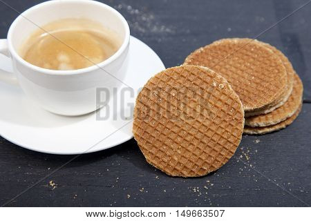 Dutch cookie stroopwafels with cup of coffee on black wooden background