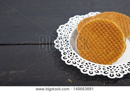 Dutch cookie stroopwafels on white plate on black wooden background