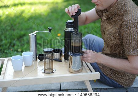 Man making fresh aeropress coffee in nature
