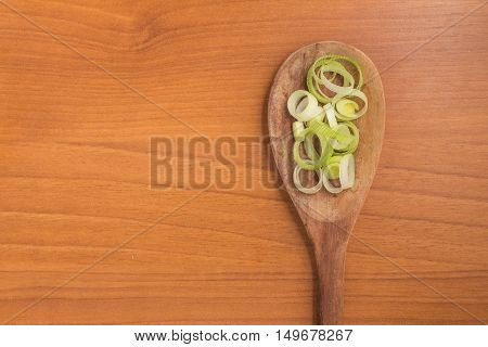 Fresh Leeks into a spoon over a wooden table