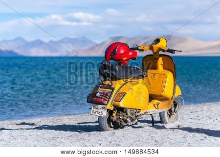 PANGONG LAKE, LADAKH, INDIA, 19 JULY 2016 : Details of Yellow scooter stopping at pangong lake against mountain layer and blue water of Pangong Lake in 19 July 2016.